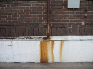 dark red brick wall foundation pipe rust