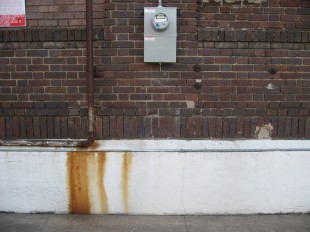 dark red brick wall foundation pipe rust meter
